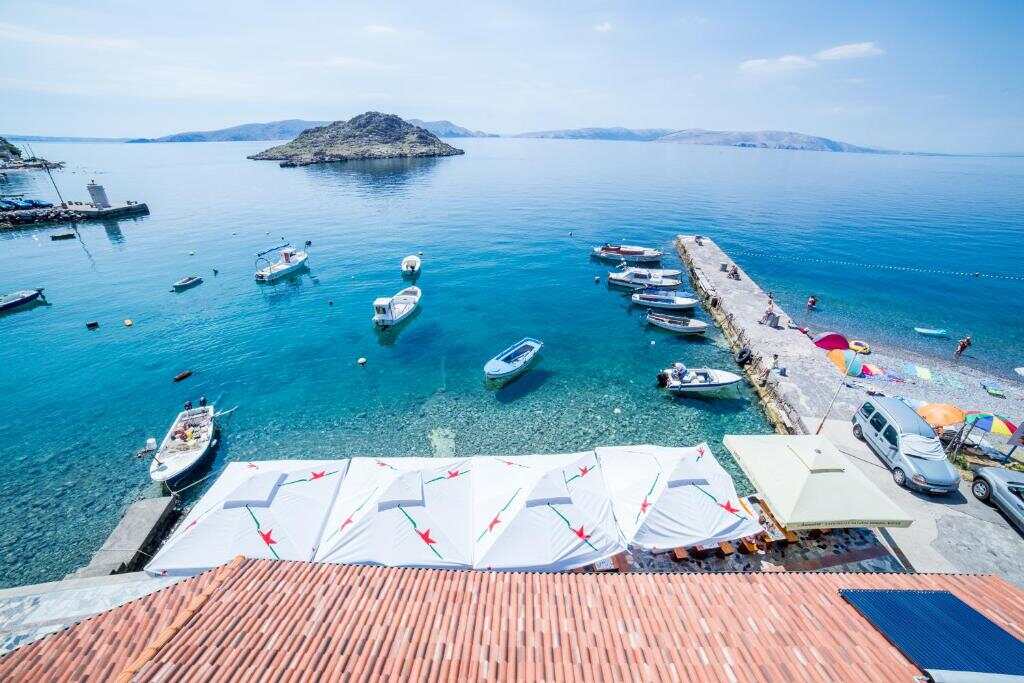 Turquoise bay with small boats and beach parasols in Sveti Juraj